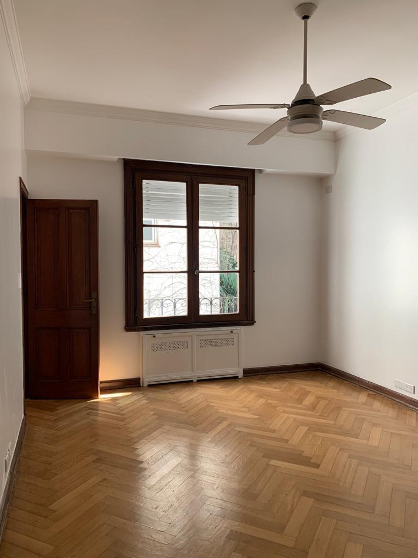 Habitación vacía con piso de madera en espiga y ventilador de techo — proyecto Montevideo, por cromo., en Recoleta